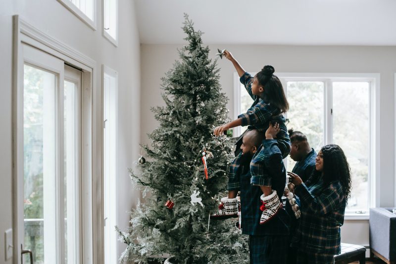 A family of 3 decorating a Christmas tree